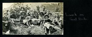 Men and women with goggles and face paint recline on a rocky slope